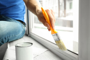 Person painting interior of home window