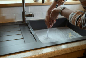 Homeowner unclogging a kitchen sink drain