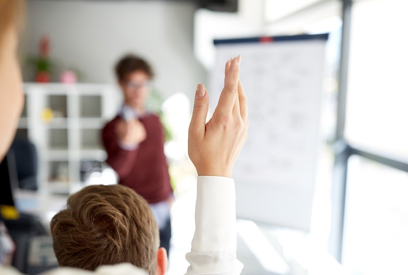 woman raising her hand to ask a question